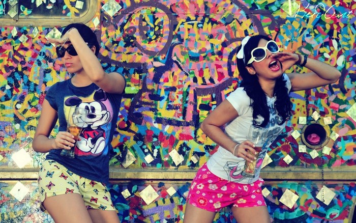 Two women dancing in front of graffiti art