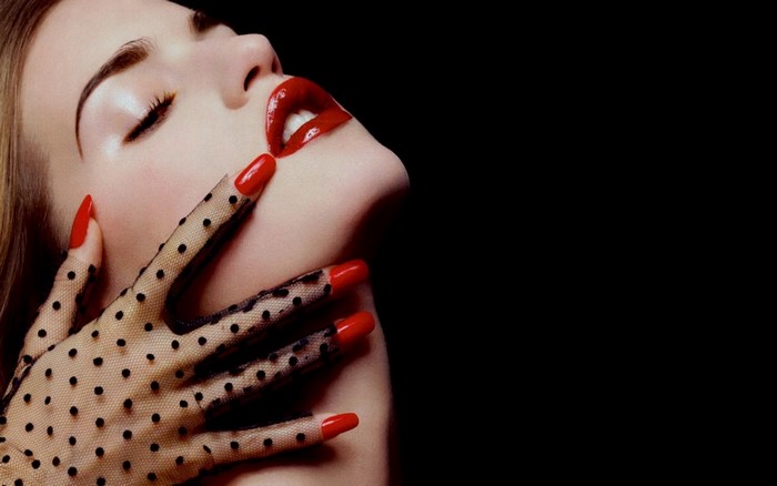 Woman with red lips and nails wearing polka dot gloves