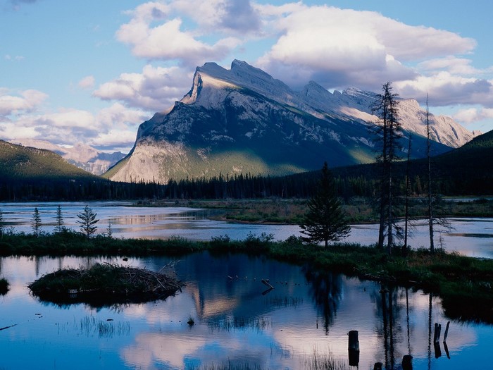 Mountain range reflected in a lake with a beaver lodge