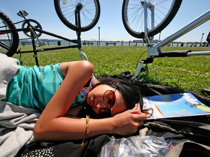 Woman sleeping next to bicycles on grass
