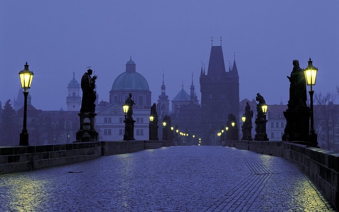 Charles Bridge at dawn with statues and gas lamps
