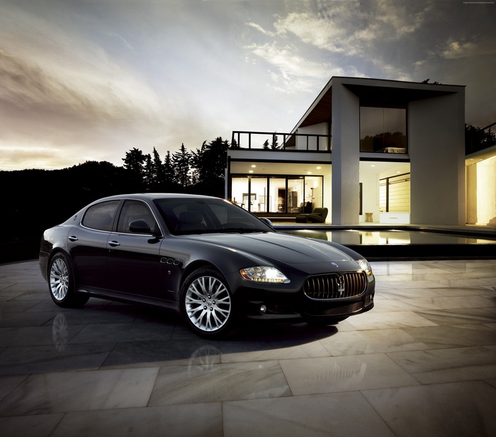 Black Maserati Quattroporte parked by a modern house