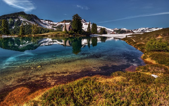 Mountain lake with reflection and a small cabin