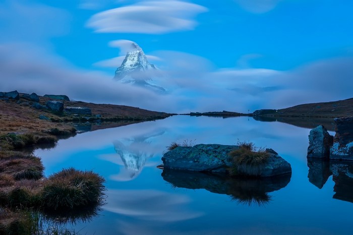 Matterhorn mountain reflected in a calm lake with clouds