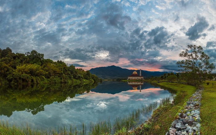 Mosque reflection on lake at sunset with mountains