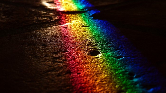 Rainbow light reflection on wet dark surface