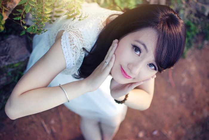Young Asian woman in white dress posing outdoors