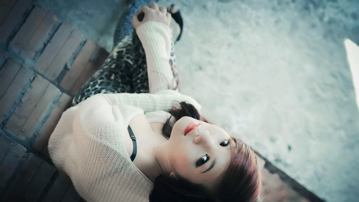 Asian woman lying down wearing a white sweater