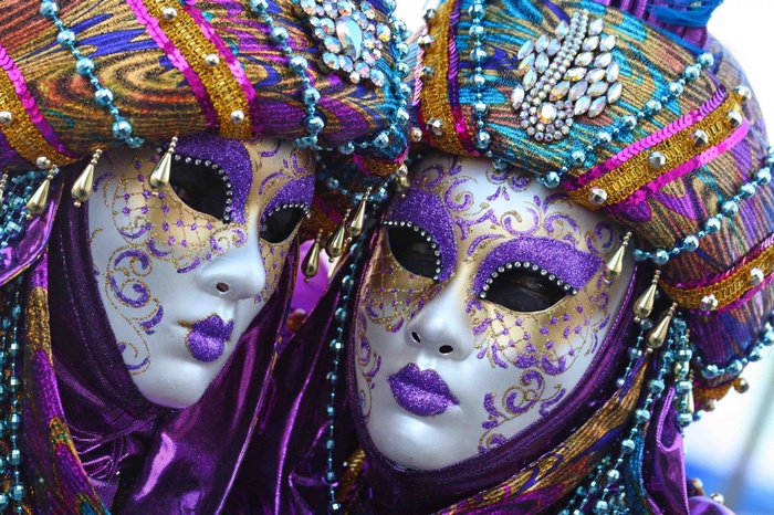 Two people in elaborate Mardi Gras masks and costumes