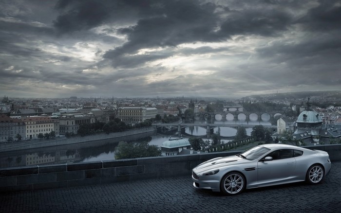 Silver Aston Martin DBS parked overlooking Prague cityscape