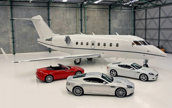 Private jet with Aston Martin sports cars in a hangar