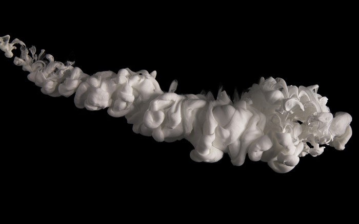 White paint swirling in water against black background