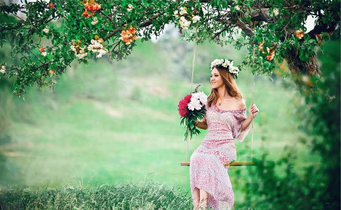 Woman Sitting on Swing with Floral Crown in Meadow