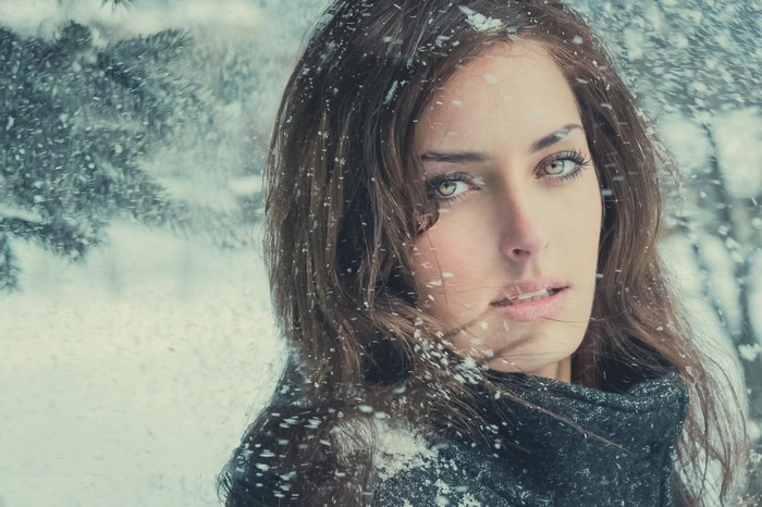 Woman with green eyes in falling snow