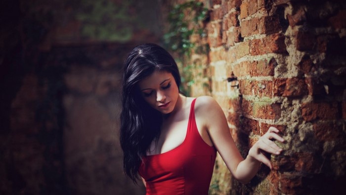 Portrait of Woman in Red Dress by Brick Wall