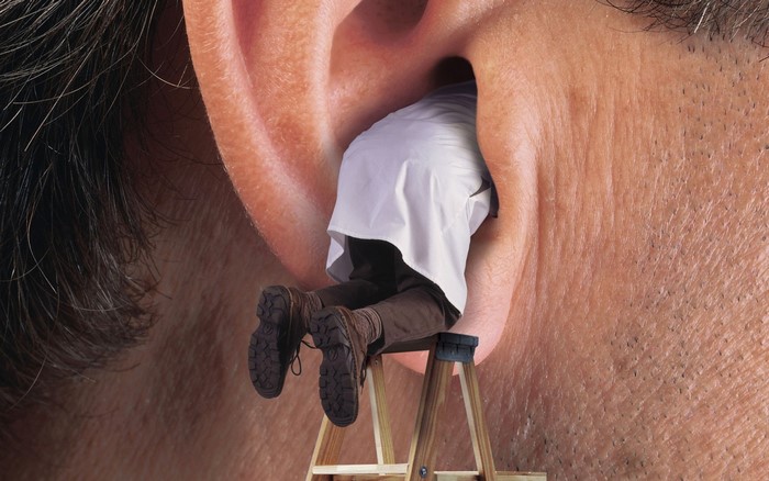 Man inside a giant ear on a ladder