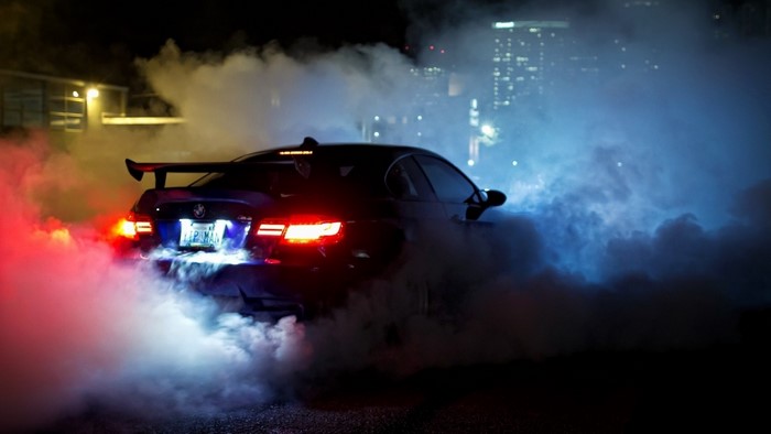 BMW M3 doing a burnout at night with city lights