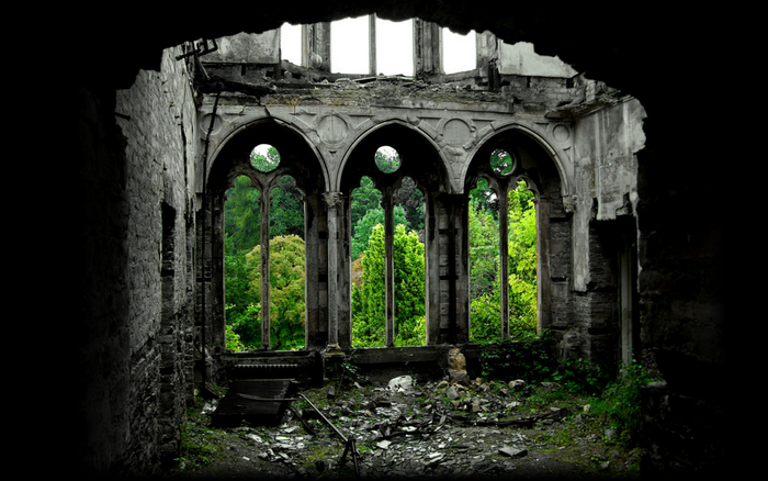 Ruined building with arched windows overlooking a forest