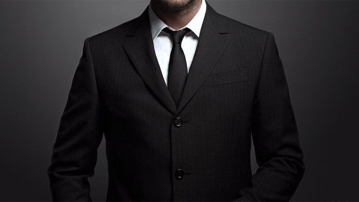 Man in a black pinstripe suit and tie