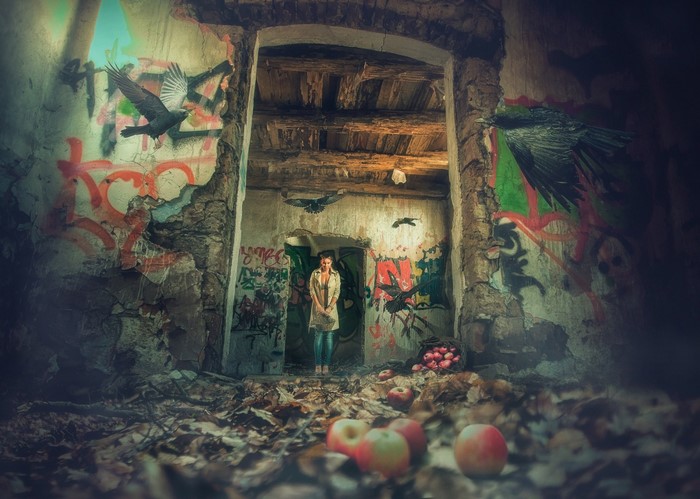 Woman in abandoned building with graffiti and crows