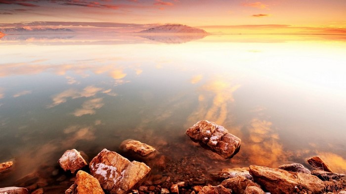 Sunset reflection over a calm body of water with rocks