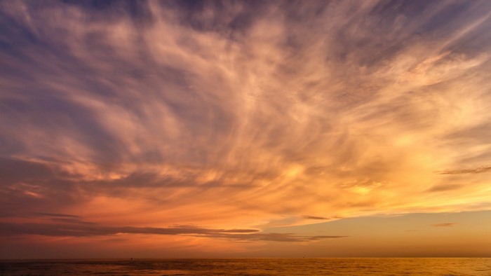 Sunset over the ocean with wispy clouds