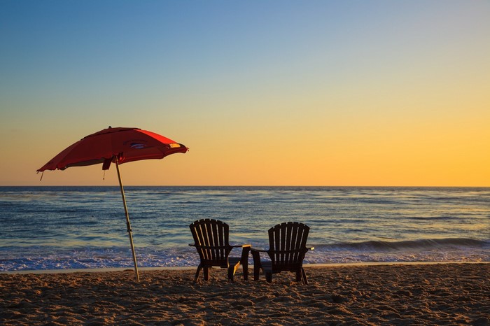 Beach chairs and umbrella at sunset