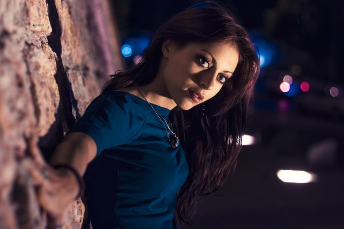 Woman leaning against a stone wall at night