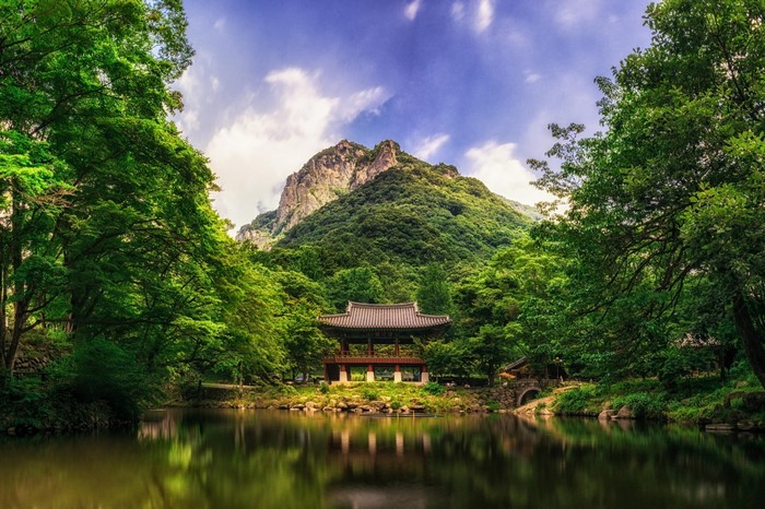 Korean pavilion by a lake with a mountain backdrop
