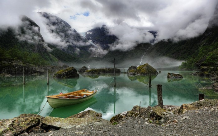 Boat on a misty glacial lake with mountains