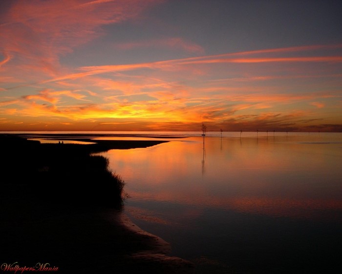 Sunset over the water with a silhouetted coastline