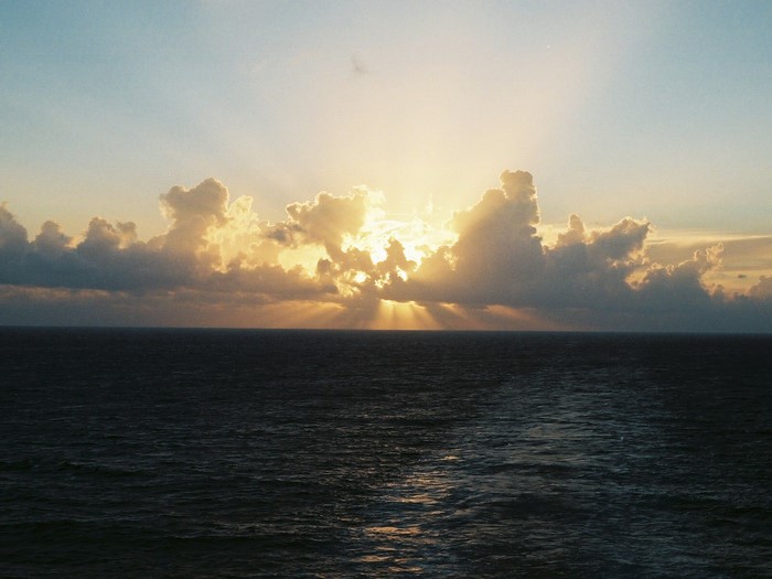 Sunlight breaking through clouds over the ocean at sunset