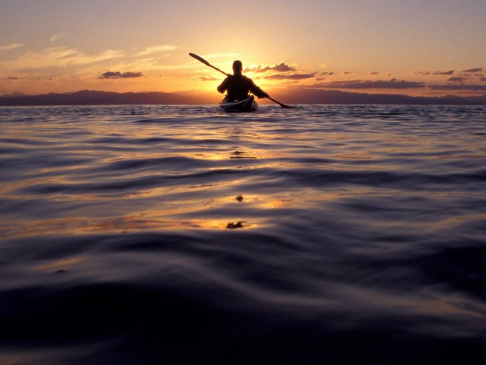 Person kayaking on the ocean at sunset
