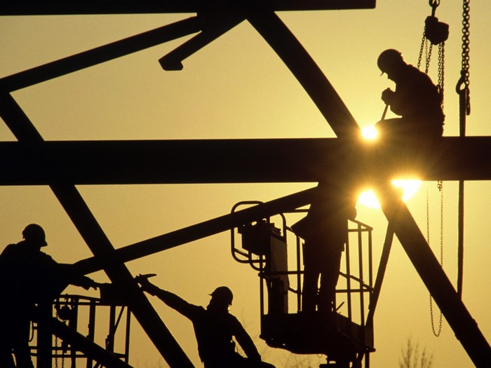Construction workers silhouetted against the sun