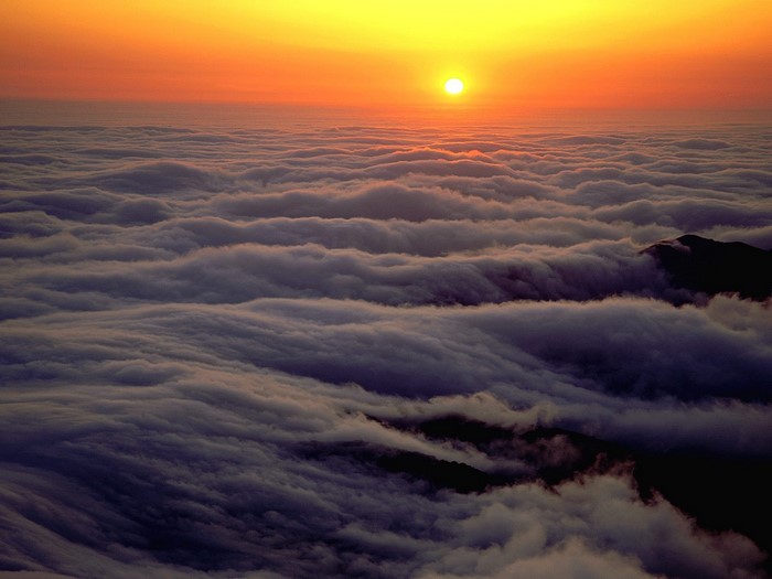 Sunset over a sea of clouds with mountain peaks