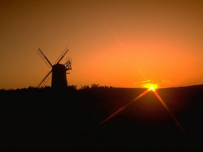 Silhouette of a windmill against a sunset sky