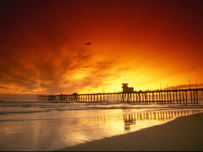 Sunset over a pier with reflection on the beach