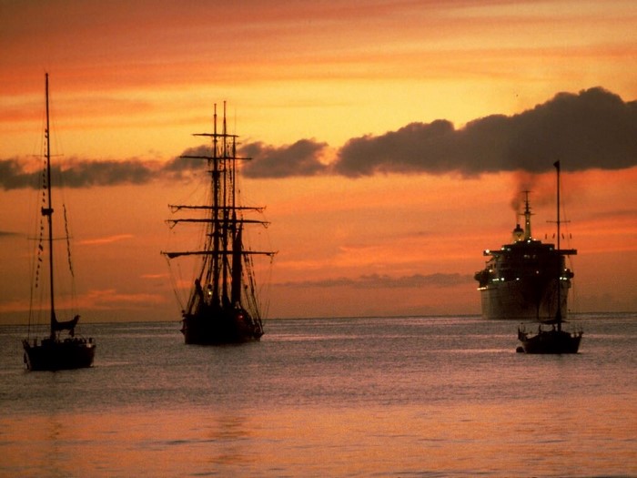 Ships sailing at sunset over the ocean