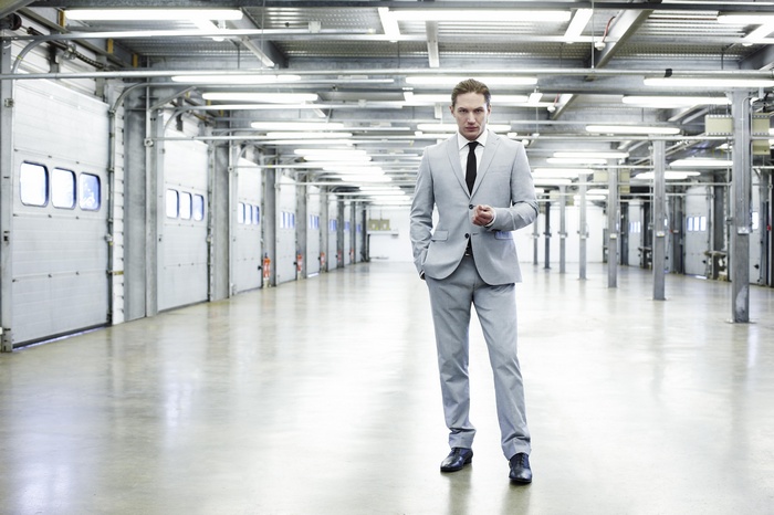 Man in a light gray suit standing in a warehouse
