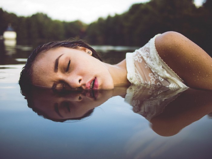 Woman lying in water with eyes closed