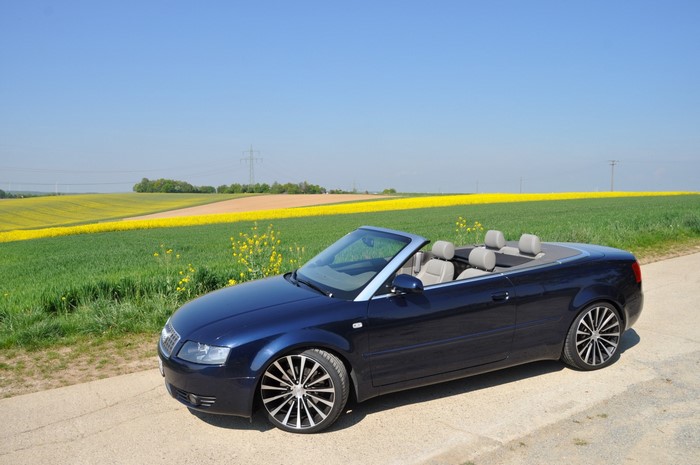 Blue Audi Convertible parked by a field of yellow flowers