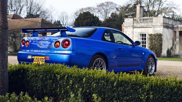 Blue Nissan Skyline R34 GT-R parked near a building