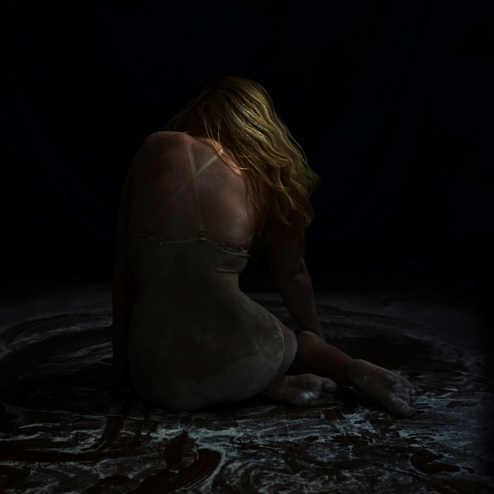 Woman sitting in flour on dark background