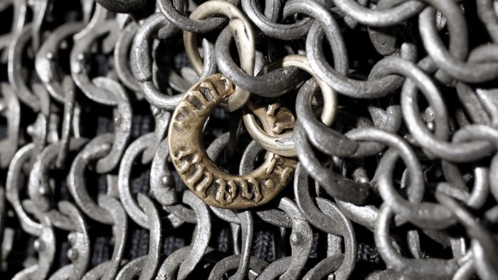 Close-up of metal chain mail with a decorative brass ring