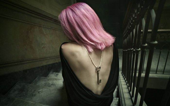 Woman with pink hair and key necklace on stairs