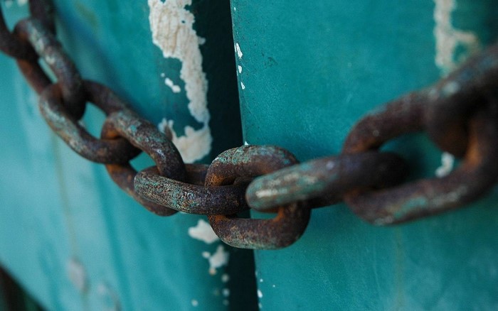 Rusty chain on a teal surface with peeling paint
