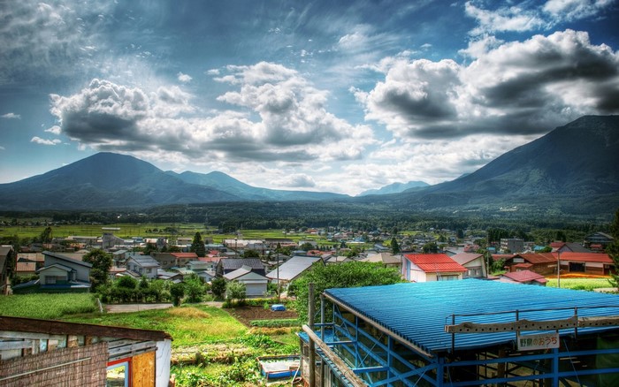 Rural village nestled in a valley with mountains under a cloudy sky