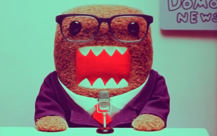 Domo-kun wearing glasses and a suit with a microphone