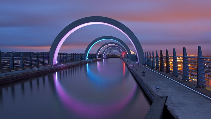 The Falkirk Wheel illuminated at dusk with colorful lights