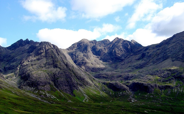 Jagged mountains under a cloudy blue sky